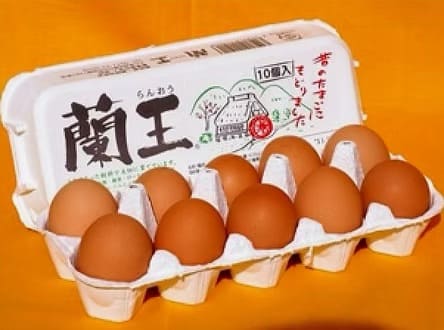 大分県産ブランド卵「蘭王」のパッケージと、並べられた茶色い卵